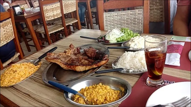 Mesa com carne assada, arroz, maionese, salada e farofa no Galpão Ventania