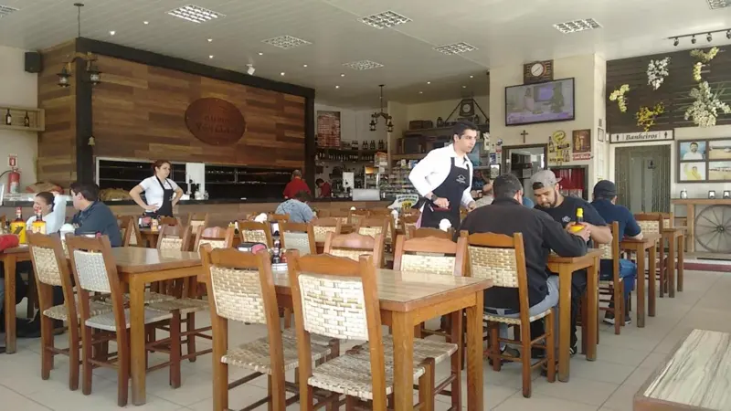 Salão do Galpão Ventania com mesas de madeira e o braseiro ao fundo